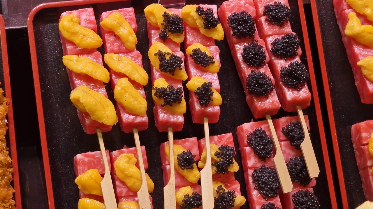 Cuisine de rue japonaise : Gros plan sur des brochettes de thon garnies de caviar et d'oursin.