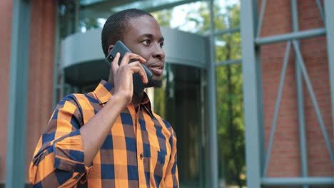 close-up view of african american man talking on the smartphone during the break near the college