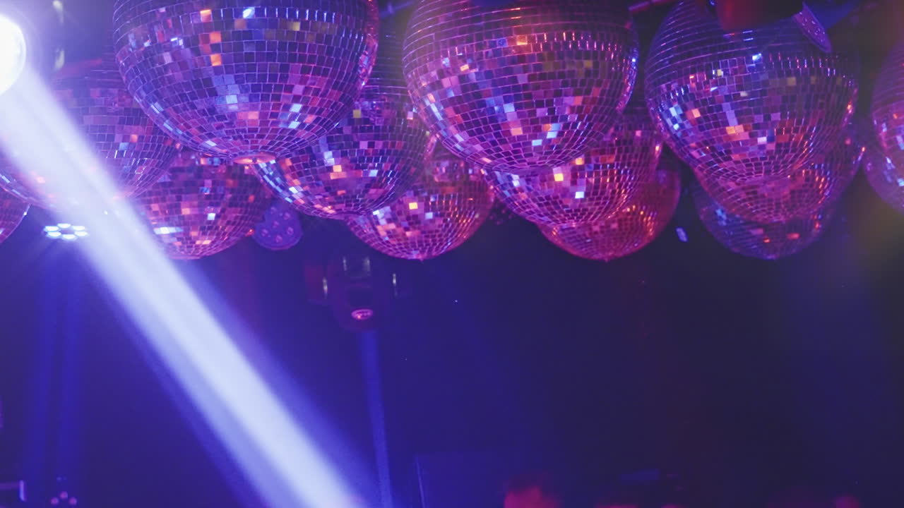 Molteplici sfere da discoteca che riflettono luci colorate per feste.