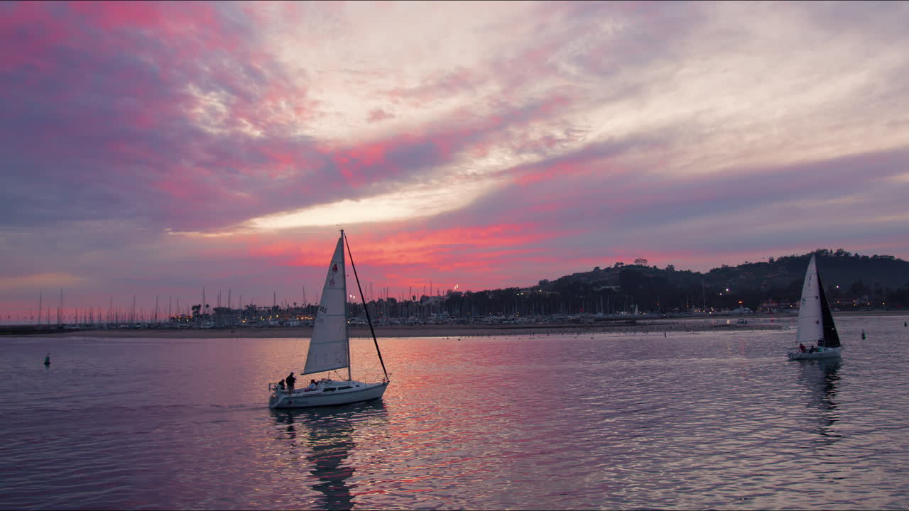 veleros que regresan al puerto con vistas a las increíbles nubes de colores durante la hermosa puesta de sol