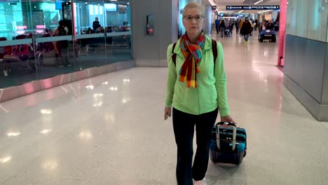 woman pulls carry on luggage through an airport with a courtesy transport pulling up to her