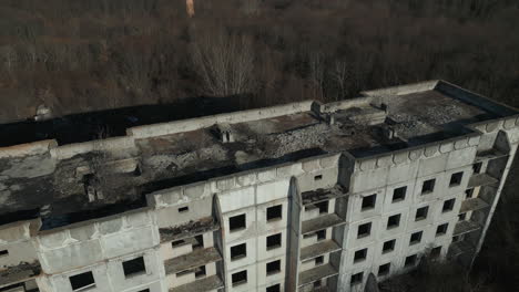 Shattered-Skies:-A-Drone's-Soaring-Tale-Over-the-Ravaged-Block-of-Flats-in-Eastern-Ukraine,-Surrounded-by-Autumn-Forest