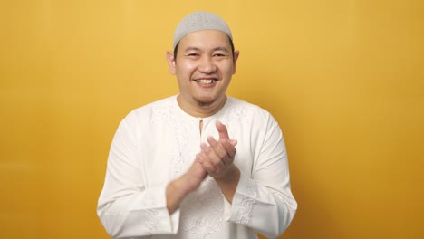 feliz hombre musulmán asiático orgulloso aplaudiendo gesto, retrato de medio cuerpo sobre fondo amarillo