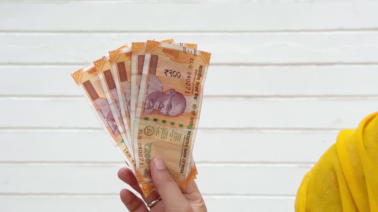 women showing two hundred rupee note, women showing her income, women showing money,