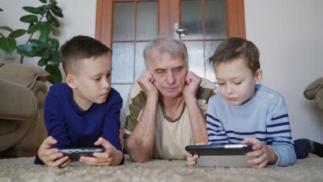 curious grandfather learning from his grandchildren how to use a tablet. peaceful pastime.