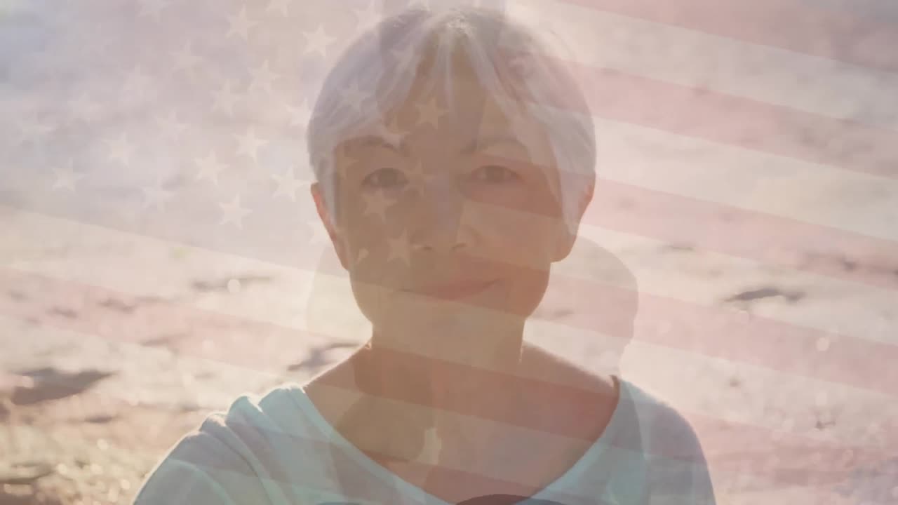 Animation of flag of united states of america over senior caucasian woman on beach