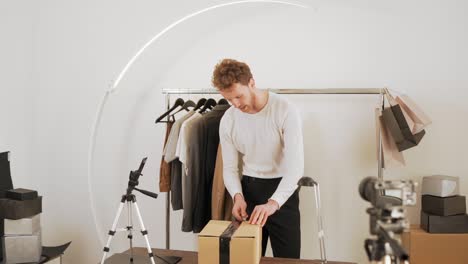 handsome stylish man unpacks box by blogging