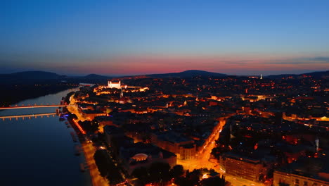 old castle illuminated at night in the historical part of bratislava, slovakia. drone footage above the danube