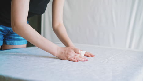 seamstress makes marks on white fabric sheet with chalk