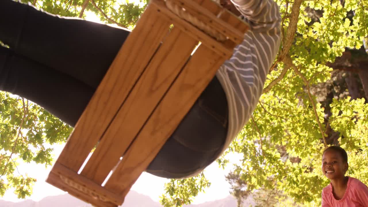 mujer jugando en los columpios con su hija