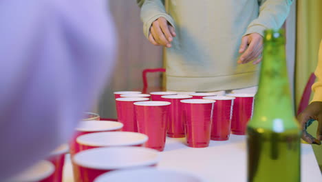 close up of unrecognizable friends playing beer pong at home