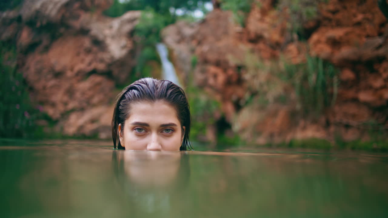 야생에서 물 표면을 들여다보는 여자. 은 머리카락의 갈색 수영