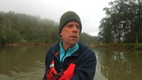 old guy paddling canoe down misty tree lined river