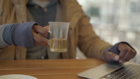 hombre afroamericano usando una computadora portátil y bebiendo té en un café