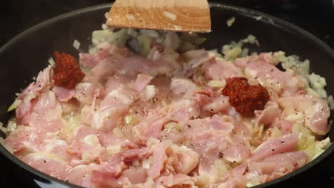 spoonfuls of curry paste added to chicken and onions in cooking pan