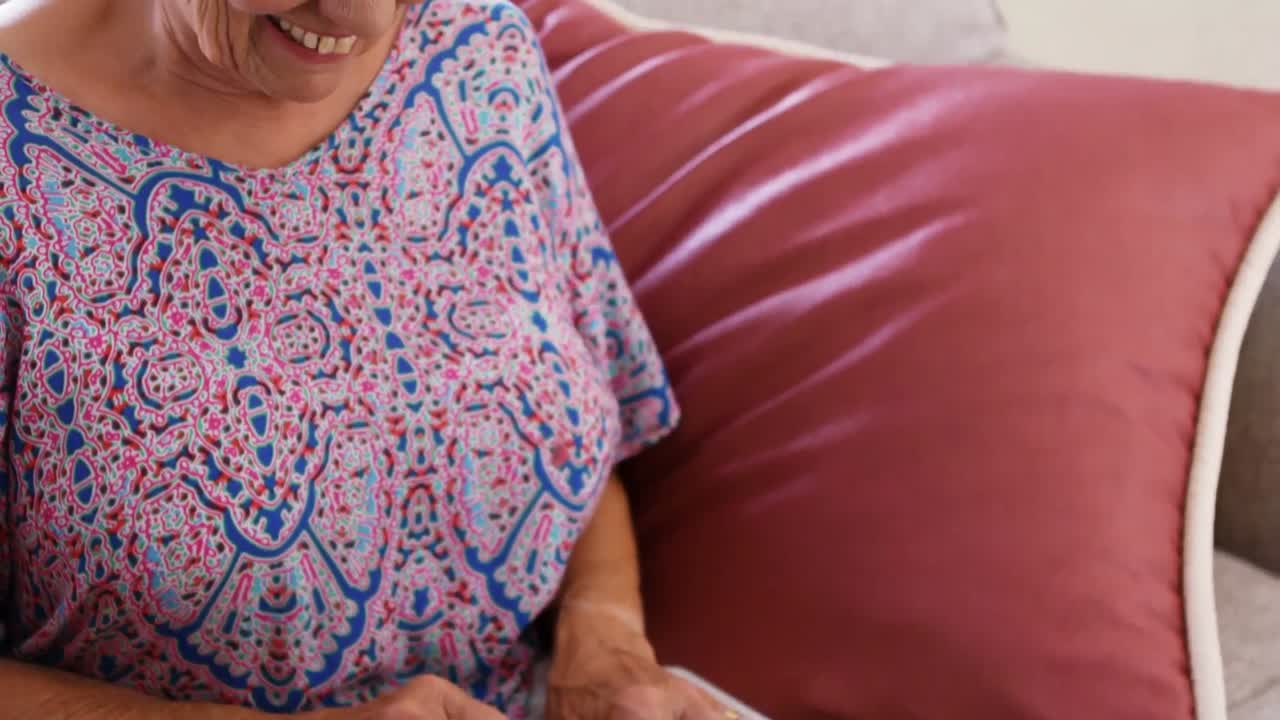 노인 여성이 노트북을 사용하면서 미소 짓고 있습니다.