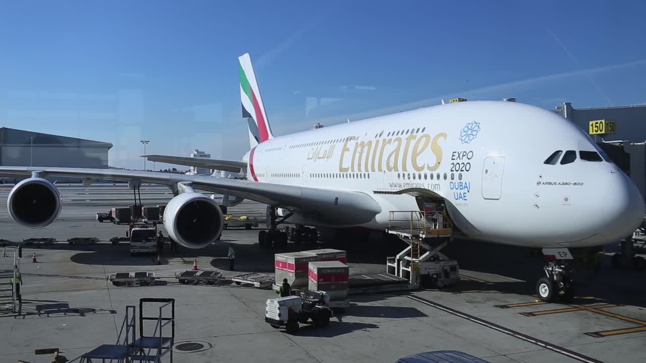 Loading luggage in a plane. Male workers are load passenger luggage into the cargo hold of the aircraft of Oman Air airline.Los Angeles International Airport, Dec. 2014