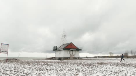 Person-walking-on-beach-to-lifeguard-house-in-winter-season