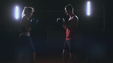 woman punches the focus mitts in the boxing gym