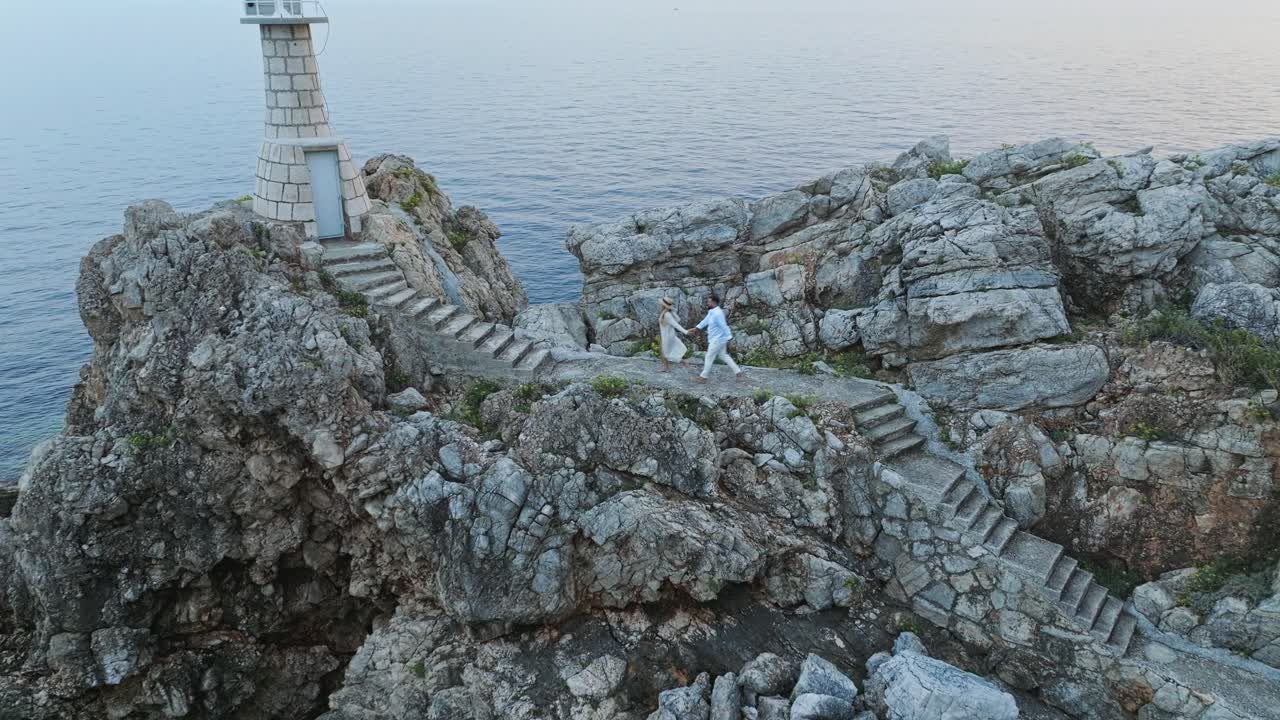 칼라모타 섬, 아드리아 해, 크로아티아 - 한 부부가 해가 지는 것을 감상하기 위해 등대 쪽으로 향하고 있습니다.