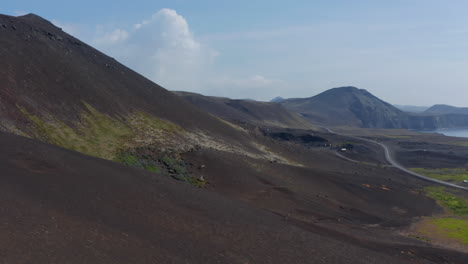 Vista-Aérea-Deslizante-Que-Revela-Un-Panorama-Increíble-De-La-Costa-De-Islandia-Con-Un-Acantilado-Negro-Volcánico.-Vista-De-Drones-Sobre-El-Campo-De-Islandia-Con-Montañas-En-El-Fondo