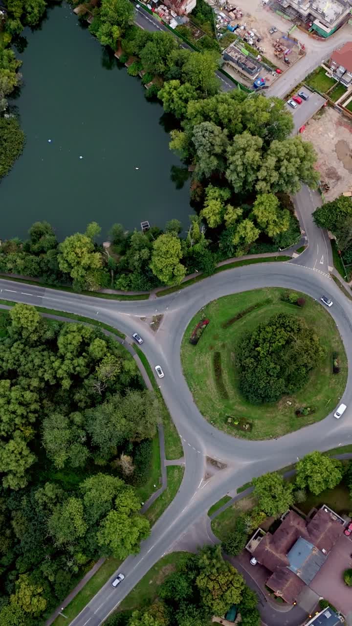 Birds-eye portrait aerial drone view over Bishop’s Waltham roundabout and pond, capturing autumn trees, village streets, and warm golden sunset light across the scenic town landscape