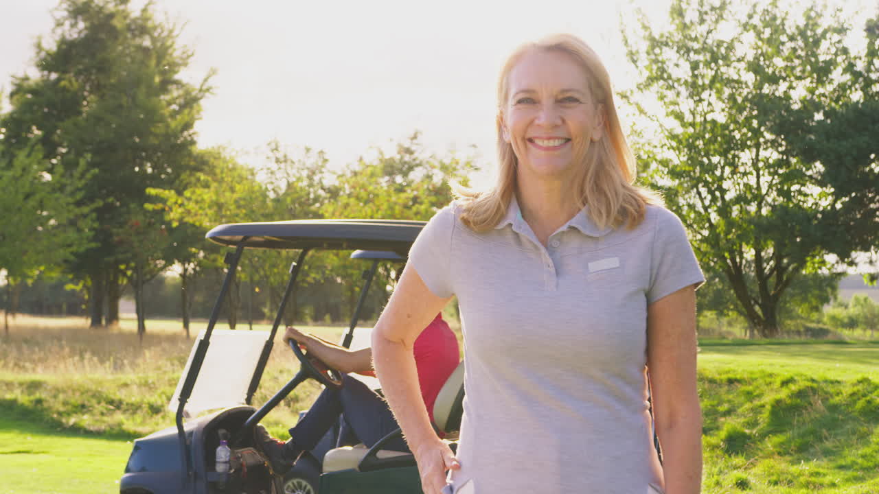 Ritratto di golfista donna matura sorridente in piedi vicino al buggy su un campo da golf