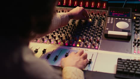 male producer working at mixing panel in the professional recording studio