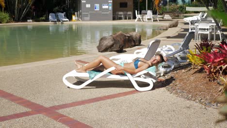 dama atractiva en bikini sexy tumbado en la tumbona de la piscina en un resort en verano