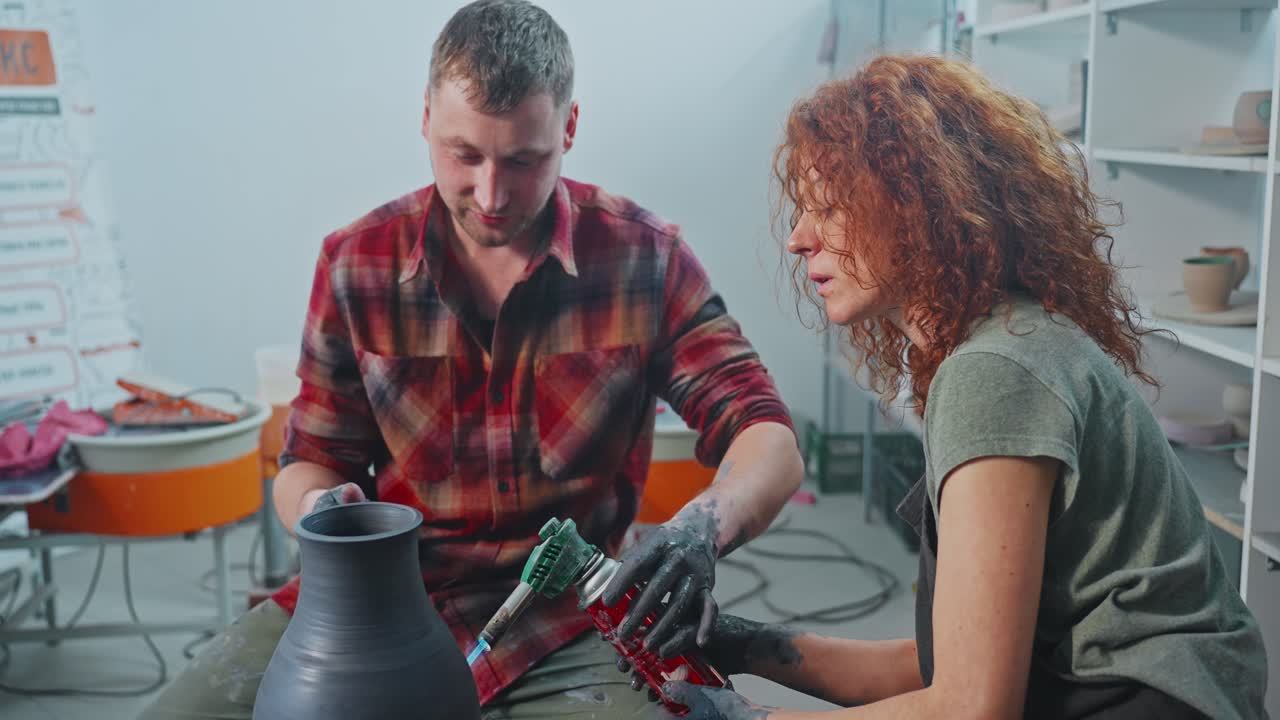 Two potters working on a pottery piece