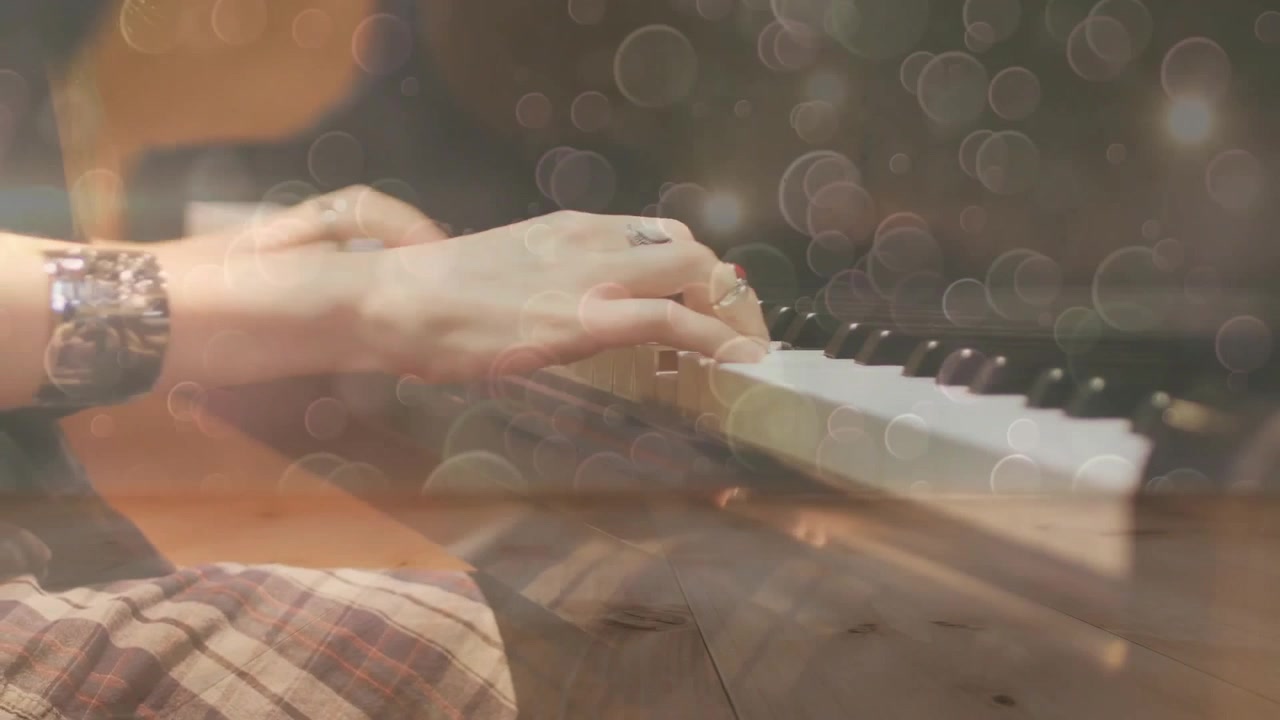 Musicista che preme i tasti del pianoforte suonando una melodia che passa da tocchi a accordi, con luci bokeh animate.