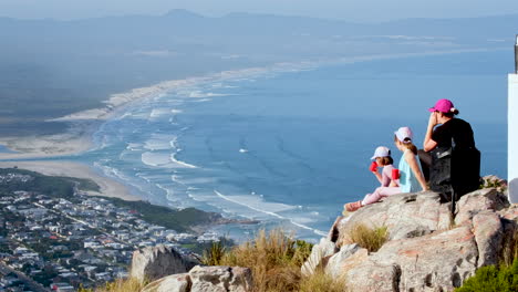 mom and daughters enjoy view of hermanus coastline from mountain viewpoint