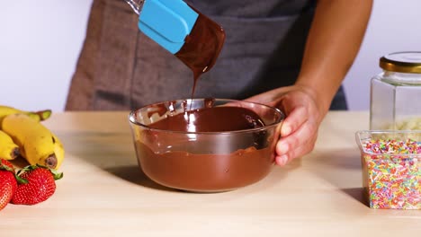 mezclando chocolate con espátula, rodeado de frutas