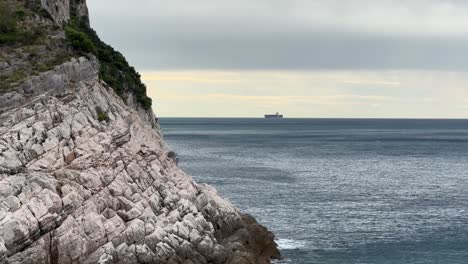white cliffs of liguria. conatiner ship at the horizon.