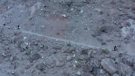 three people on dirt bikes cruising down gravel road at high speed