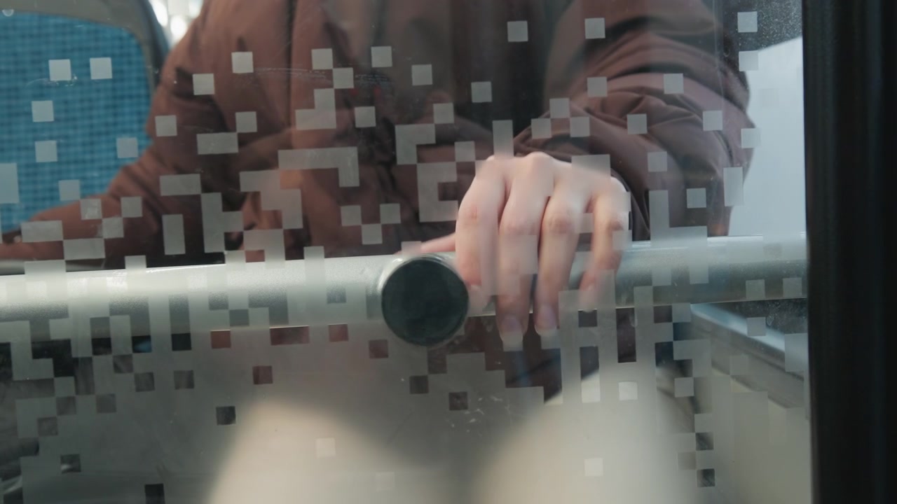 Close chest-height view shows hands firmly gripping horizontal metal rail behind textured frosted glass, with shifted fingers and slight blur suggesting pushing, bracing, and steady movement indoors