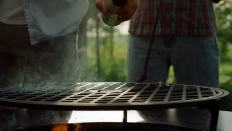 male person getting ready for bbq party outside. man chef spraying oil on grille