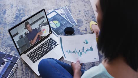 African-american-woman-holding-a-document-having-a-video-call-with-female-colleague-on-laptop