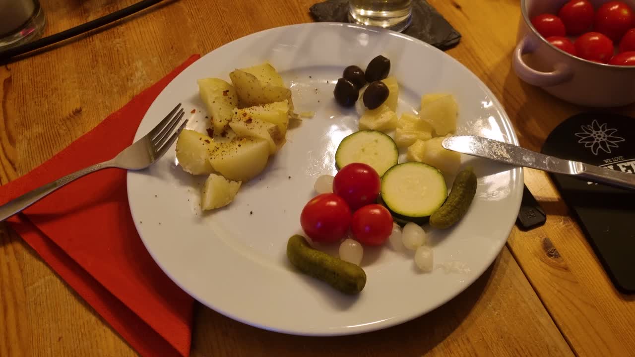 Plate of traditional Swiss raclette accompaniments on a wooden table with spices, ready for melting cheese, showcasing Swiss culinary culture in Bern during winter