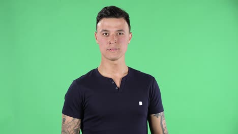 retrato de un joven guapo está mirando a su alrededor hablando de algo y luego haciendo un gesto de silencio secreto. pantalla verde