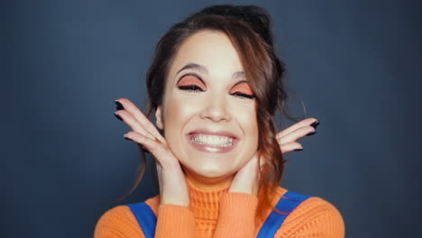 chica joven en suéter naranja haciendo cara de asombro y regocijo