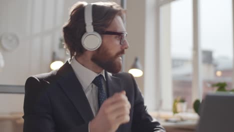 young businessman in headphones enjoying music during office workday