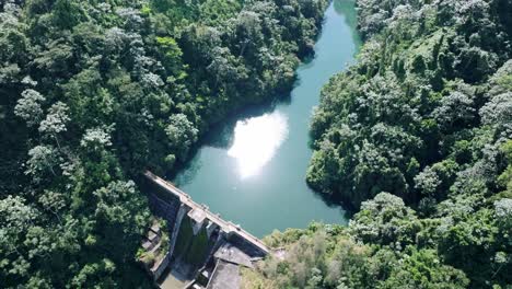 aerial top down shot of tireo dam with green river and green nature during sunny day in bonao, dominican republic