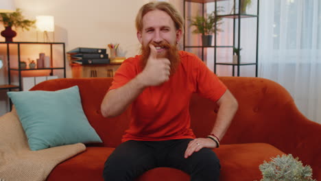 happy young man looking approvingly at camera showing thumbs up, like positive sign, good news