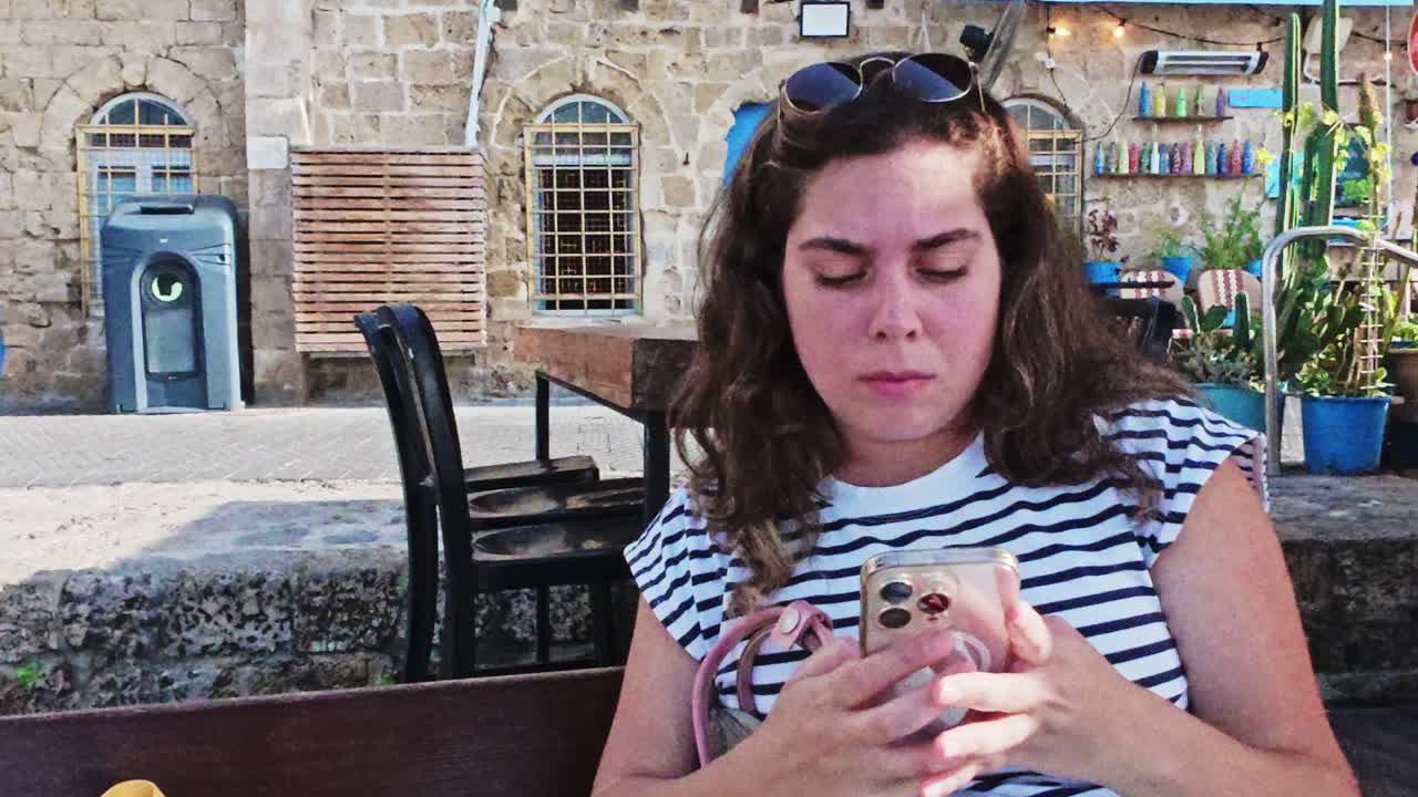 Koncentreret kvinde læser besked på telefon i den gamle by Jaffa