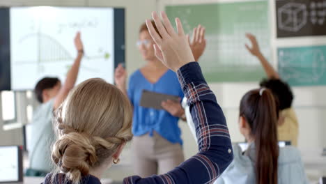 in high school, students raising hands to answer teacher's question in classroom