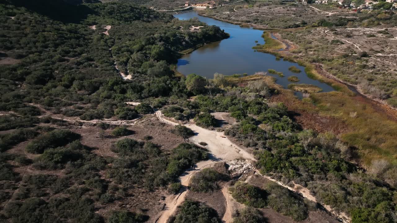 Slow-motion closeup drone view of Calavera hills and the lake on a sunny day offering 6+ miles of dirt biking and hiking trails at the northern part of San Deigo, Carlsbad California