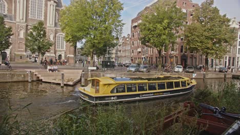 el barco turístico eléctrico de ámsterdam navega sobre el canal en el centro de la ciudad de ámsterdam