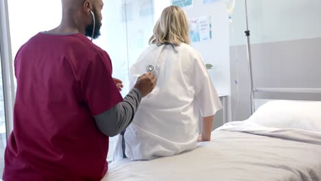 African-american-male-doctor-with-stethoscope-examining-caucasian-female-patient-at-hospital