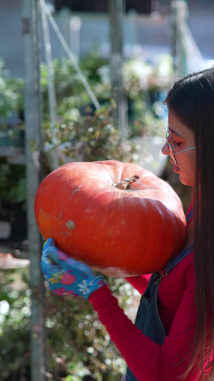 정원 센터 에서 큰 호박 을 들고 있는 여자